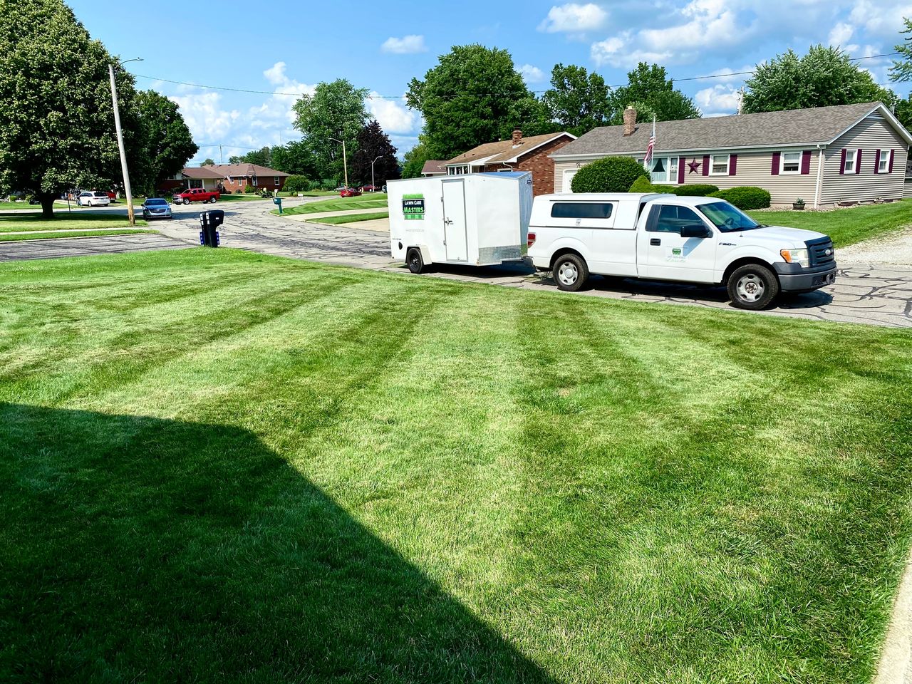 Lawn Care Masters mowing truck and trailer beside a completed property